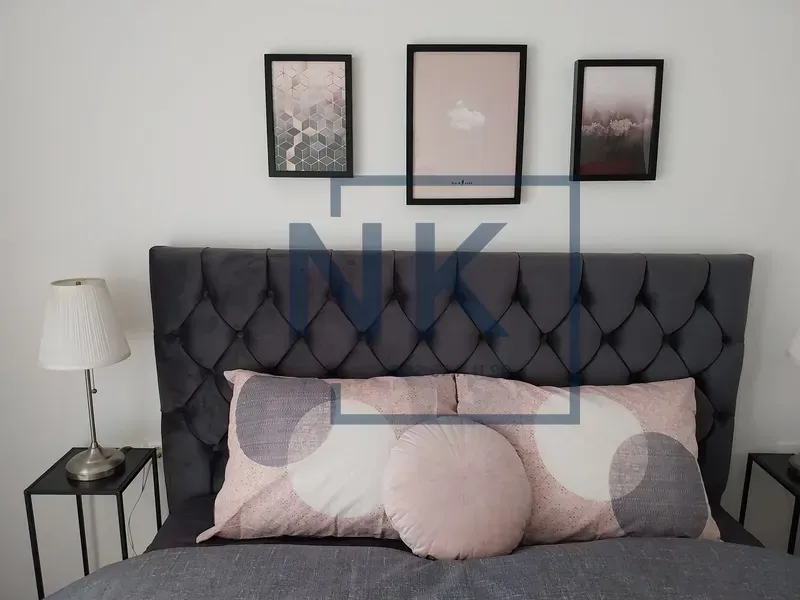 Double bed with a tufted headboard, nightstands, and framed pictures on the wall.