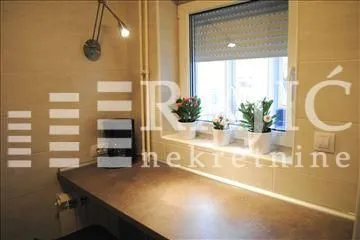 Small kitchen with a counter and a window with potted plants. - image 6