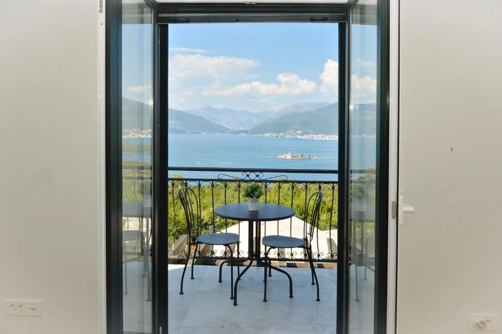 View of the sea and mountains from the terrace through open balcony doors.