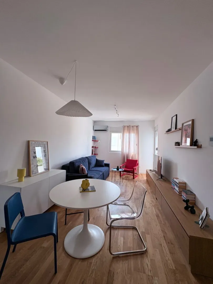 Living room with dining area, sofa and wooden flooring.