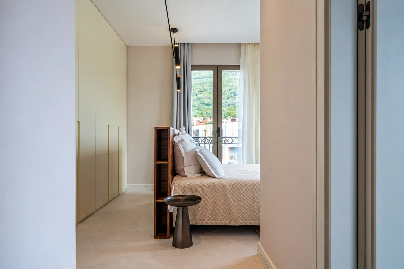 View from the hallway into a modern bedroom with a built-in wardrobe and a double bed.