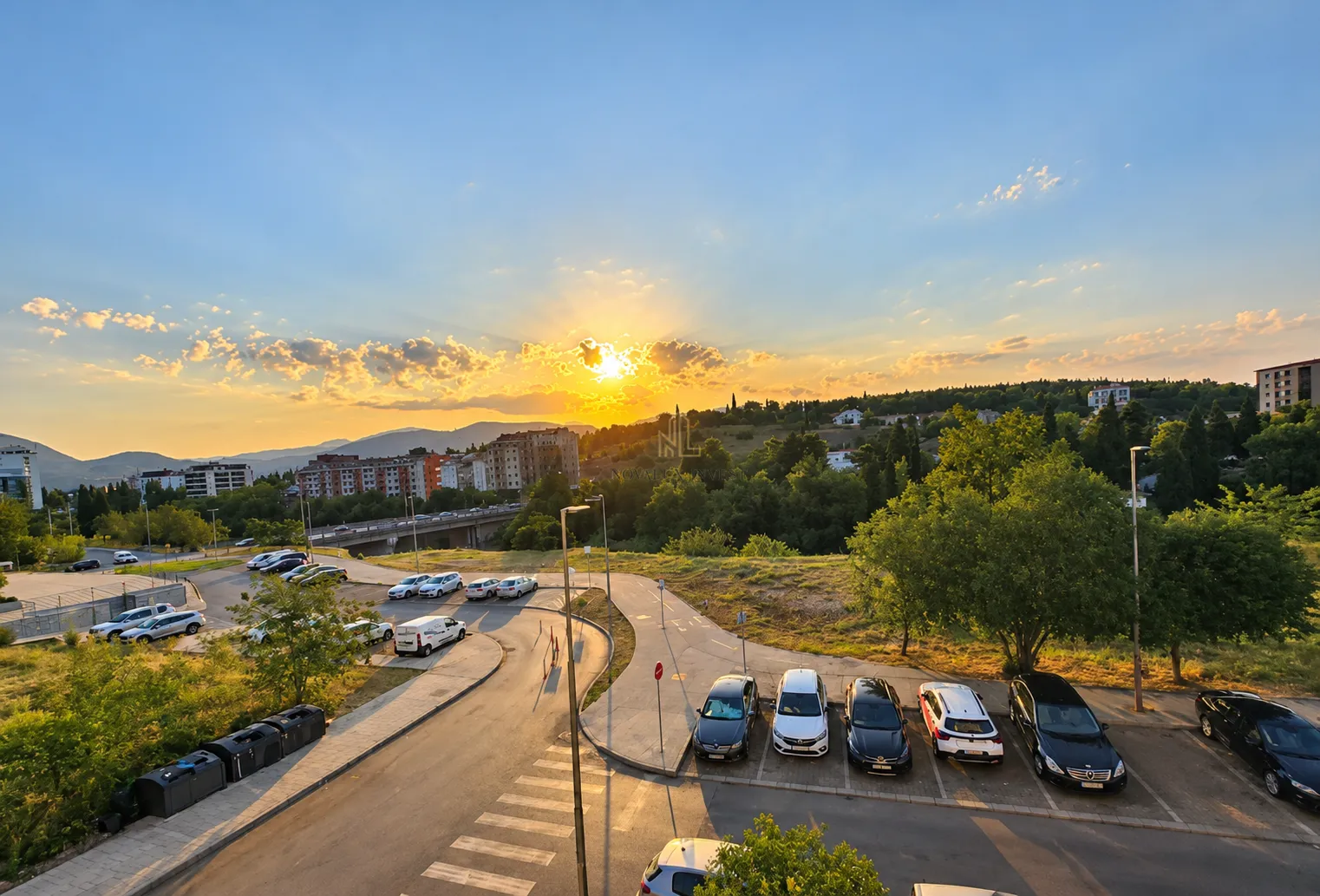 Pogled iz apartmana na grad i okolni pejzaž u toku zalaska sunca.