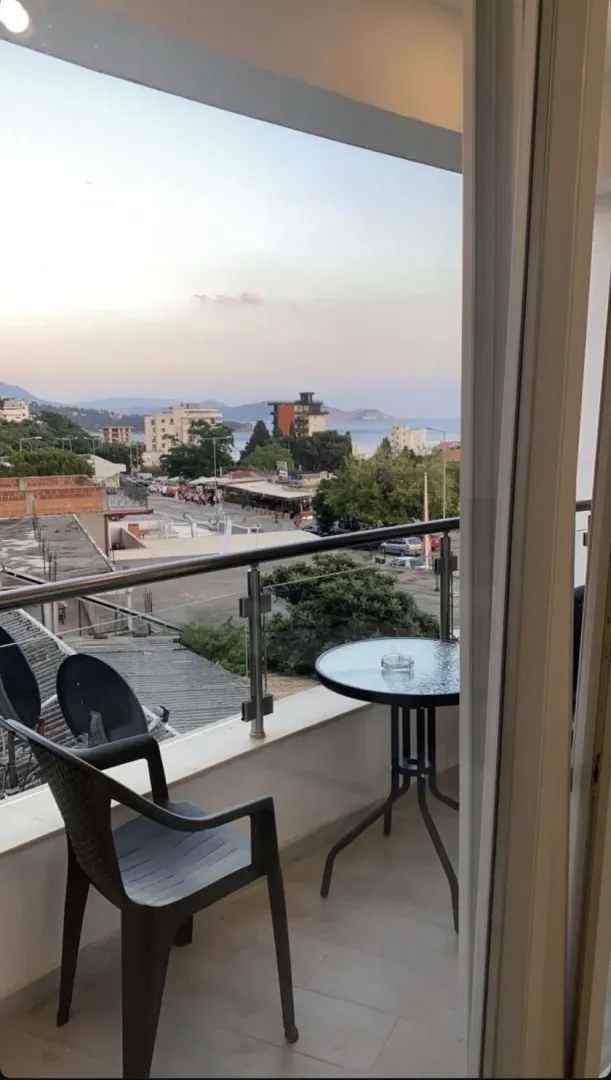 Namješten balkon sa stolom i stolicama i pogledom na grad i more.
