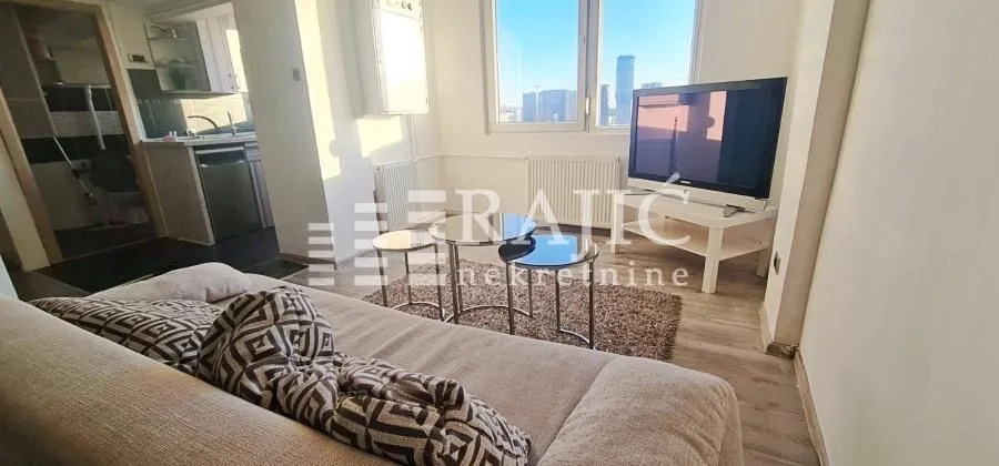 Living room with a sofa, TV, and a view through the window.