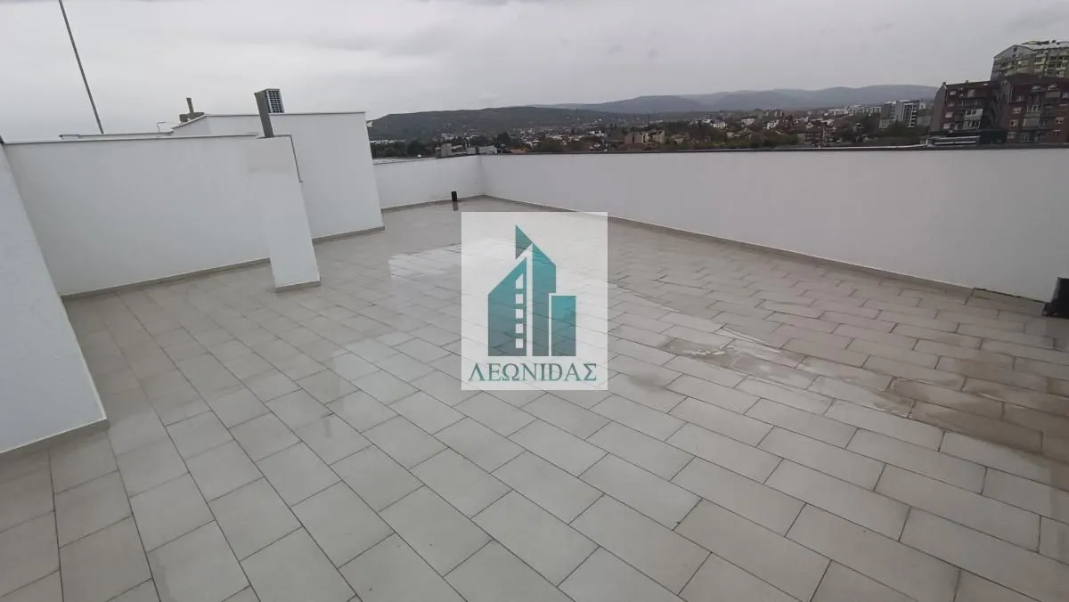 Velika prostrana terasa sa pločicama i pogledom na grad.