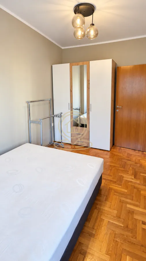 Bedroom with a bed, wardrobe and parquet flooring.