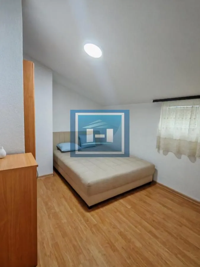 Small attic bedroom with a double bed and wooden flooring.