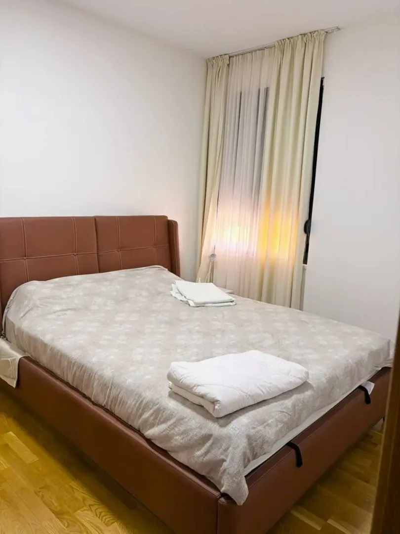 Spavaća soba sa bračnim krevetom i svijetlim zavjesama.