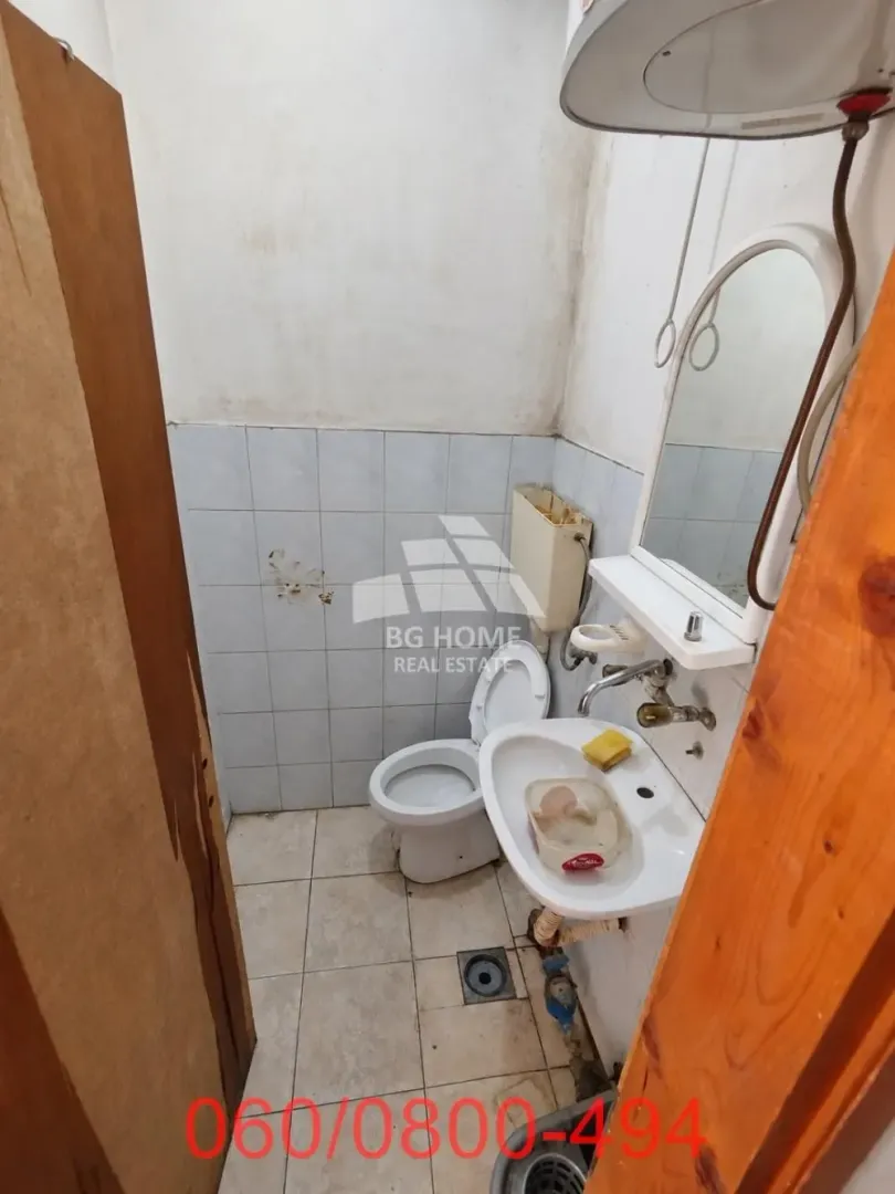 Smaller bathroom with a toilet, sink and mirror.