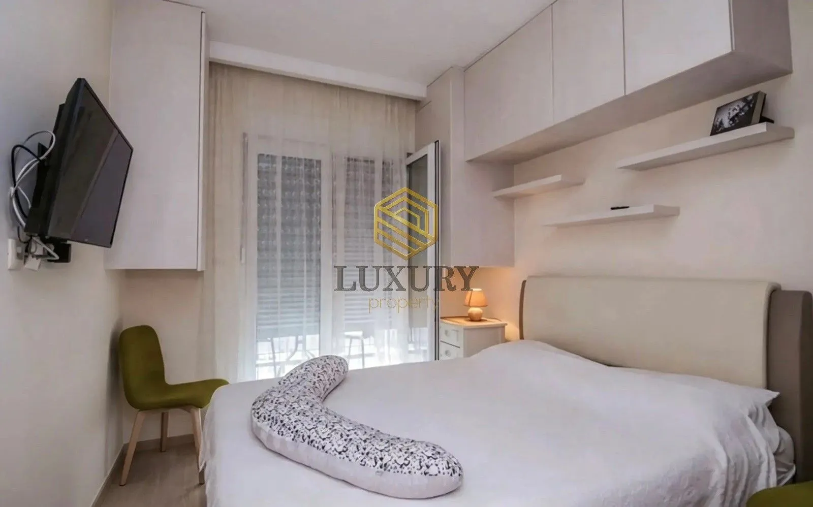 Modern bedroom with a double bed, built-in cabinetry, and a green chair.