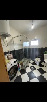 Kupatilo sa tuš kabinom, mašinom za veš i crno-bijelim pločicama na podu. - image 14