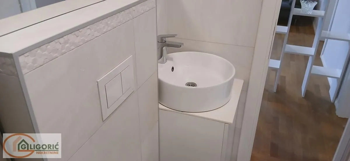 Pogled na umivaonik i deo kupatila sa pločicama.