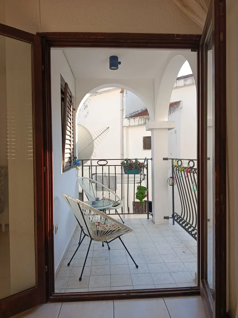 Covered terrace with seating furniture and a courtyard view.
