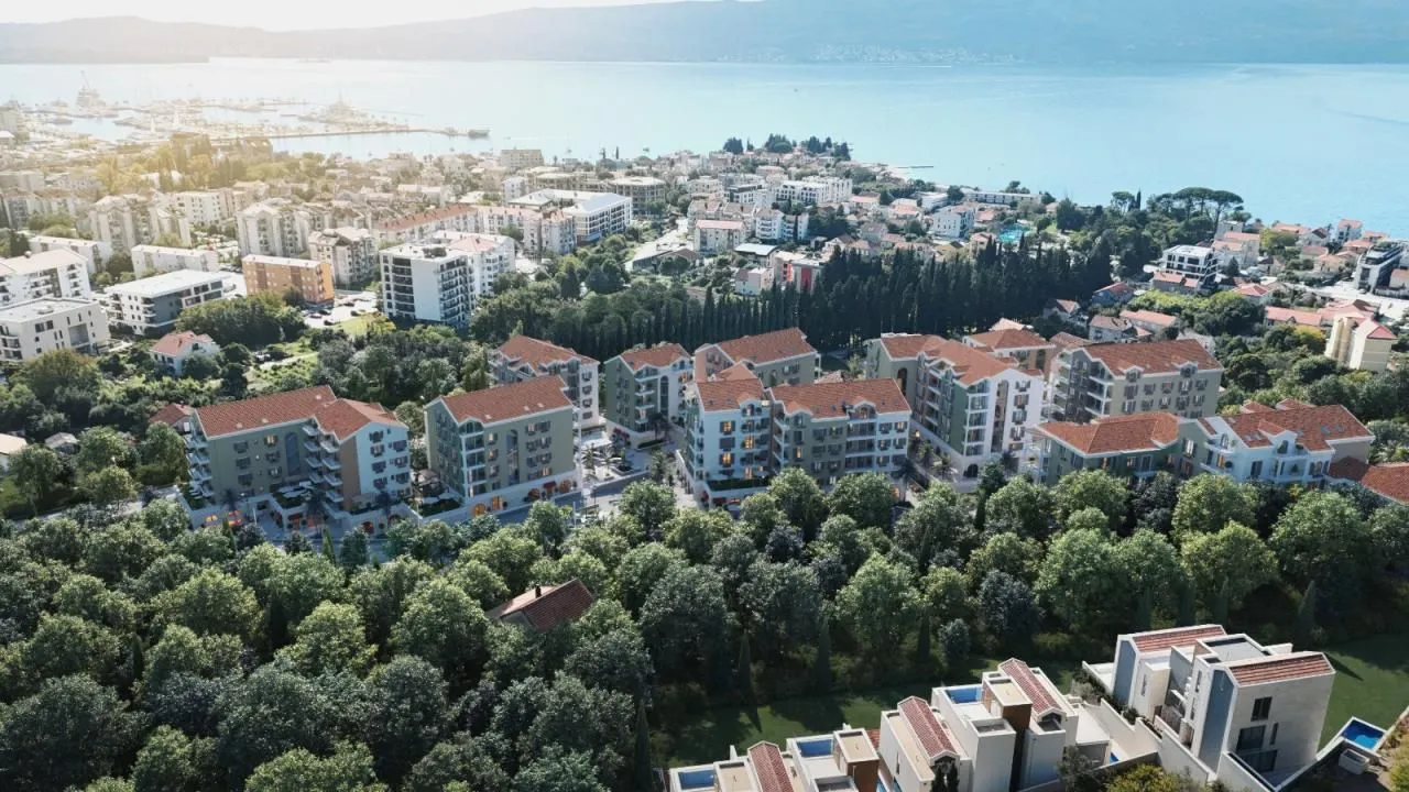 Pogled iz vazduha na kompleks zgrada okružen zelenilom u blizini mora.
