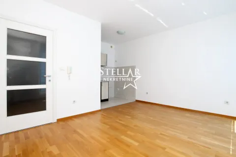 Empty living room with wooden flooring and a view of the kitchen in the background. - image 4