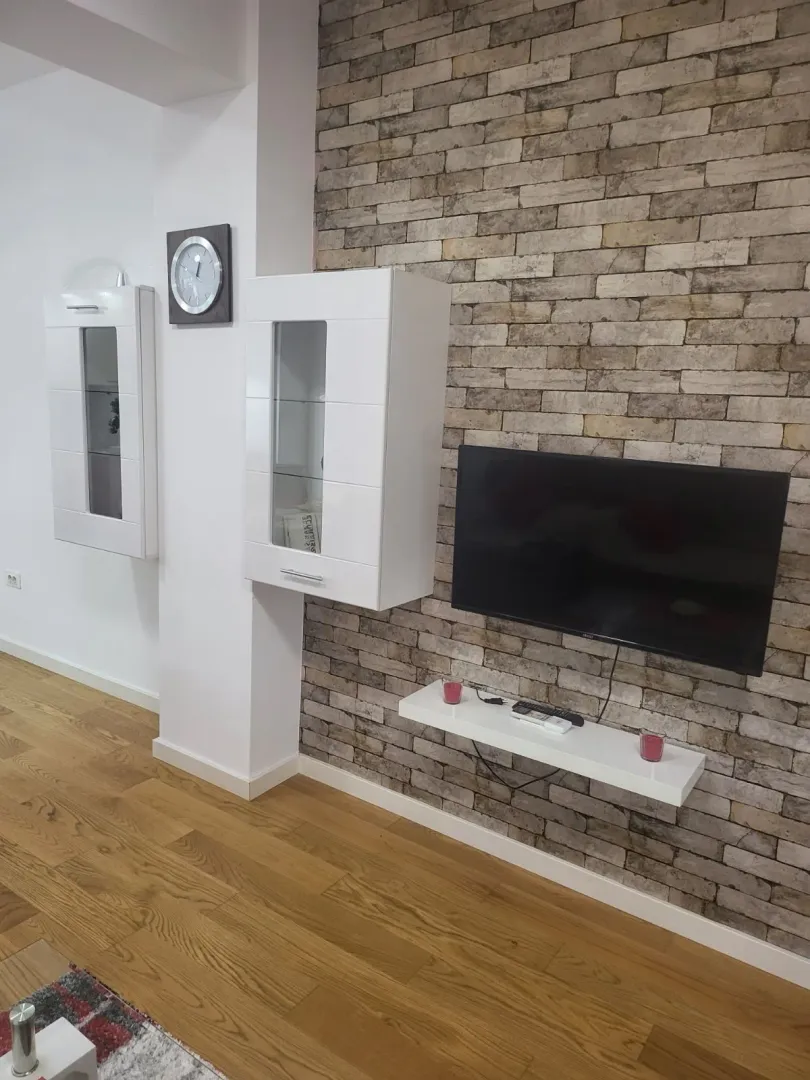 Part of a living room featuring a decorative brick wall and a wall-mounted TV.
