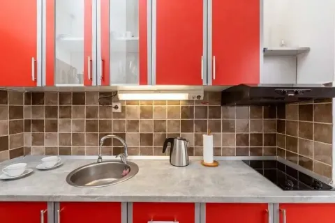 Kitchen with red cabinets, a sink, and a built-in cooktop. - image 10