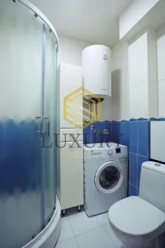 Compact bathroom with a shower cabin, washing machine, and water heater. - image 9