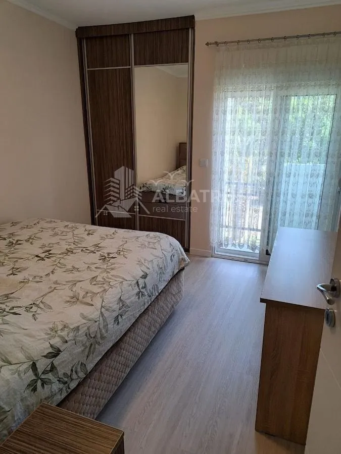 Namještena spavaća soba sa bračnim krevetom, garderoberom i izlazom na terasu.