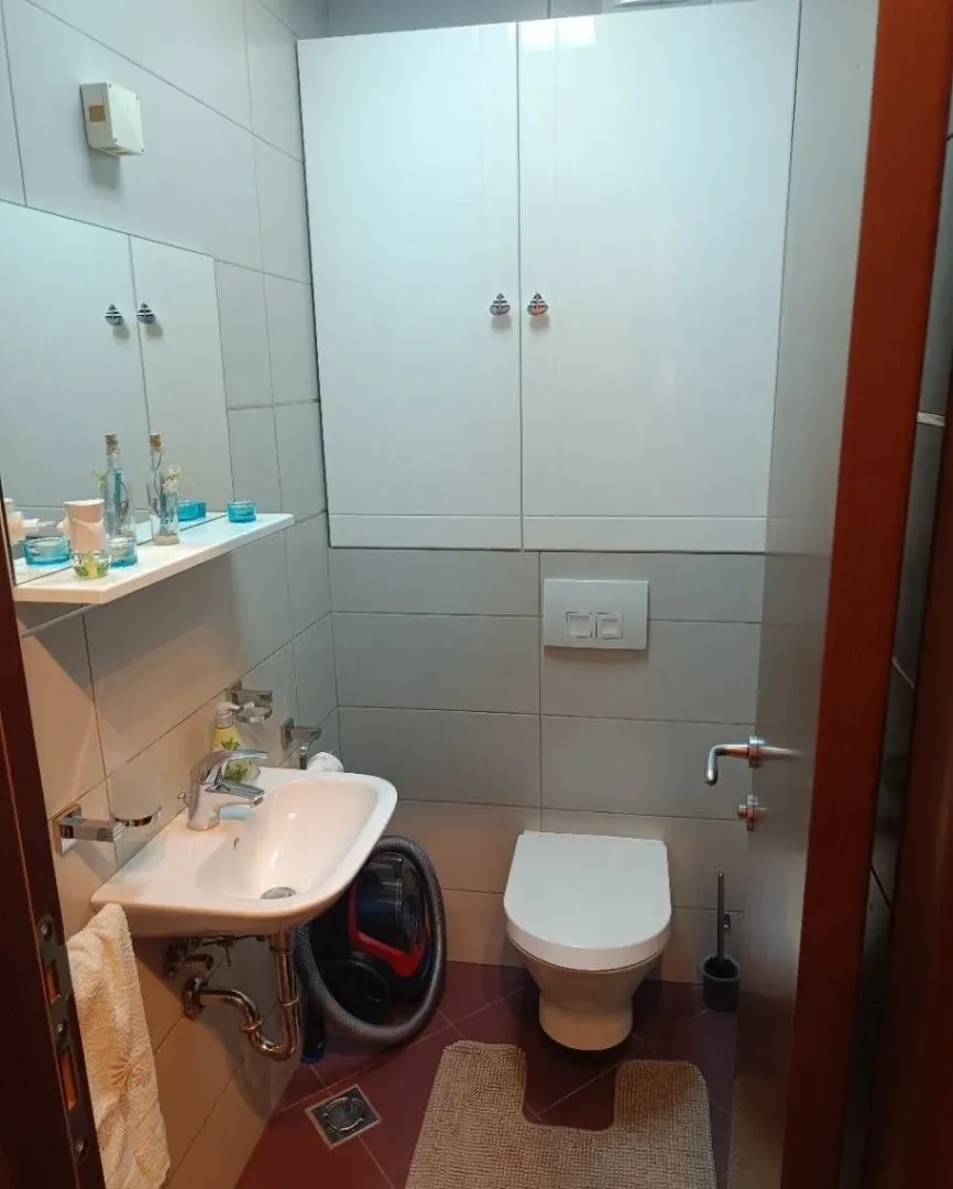 Manje kupatilo sa umivaonikom, WC šoljom i bijelim visećim elementima.