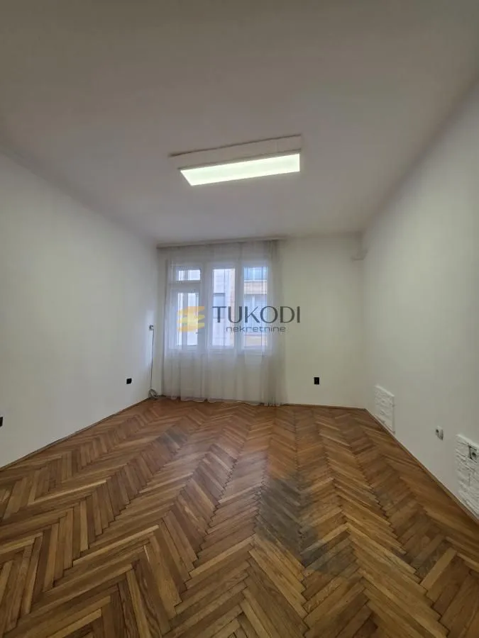 Empty room with hardwood flooring and white walls.