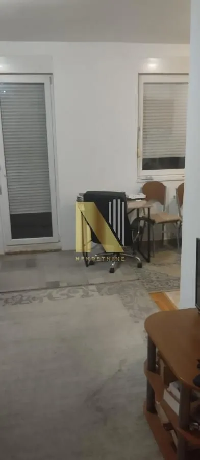 Dnevna soba sa radnim stolom i izlazom na terasu.