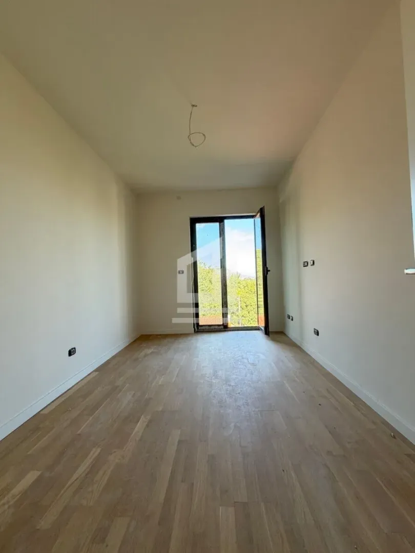 Prazna soba sa drvenim podom i izlazom na terasu.