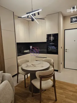 Modern kitchen with built-in appliances and a dining table with chairs. - image 21