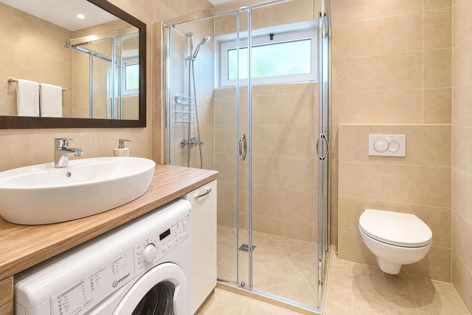 Modernly equipped bathroom with a shower cabin, washbasin, and washing machine.