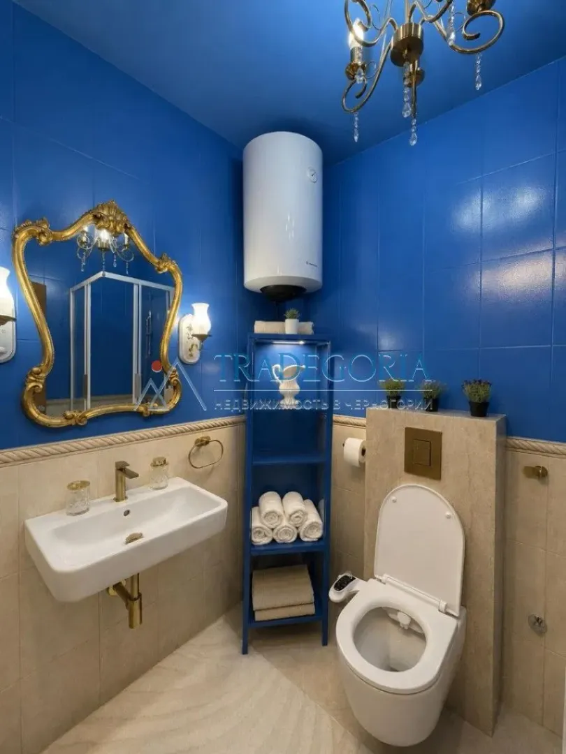 Kupatilo sa plavim pločicama, lavaboom i ugradnom wc šoljom.