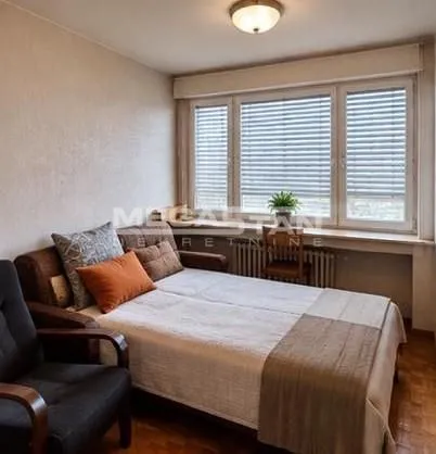 Small bedroom with a bed and a window with blinds.