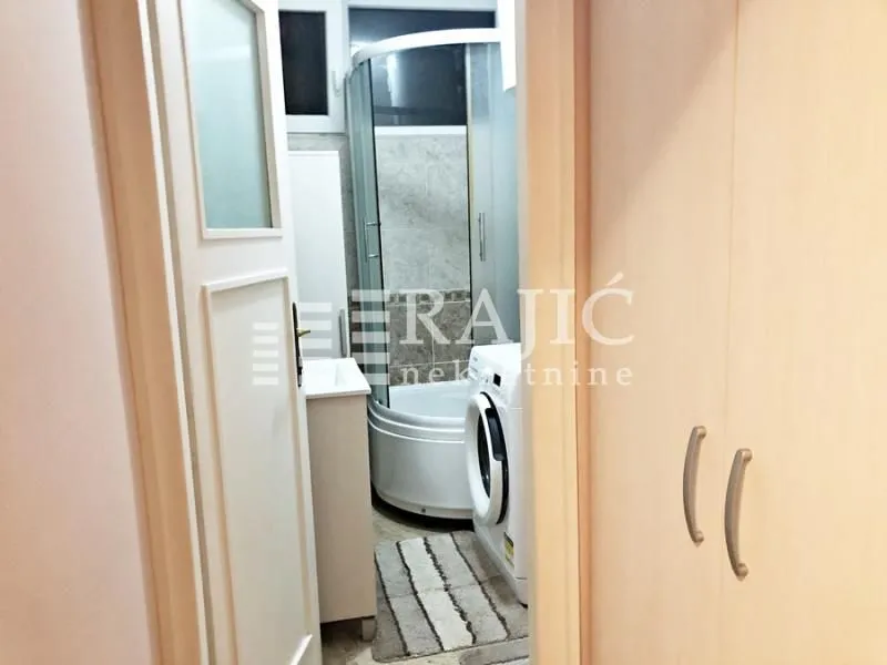 View of the bathroom with a shower cabin through the open door.