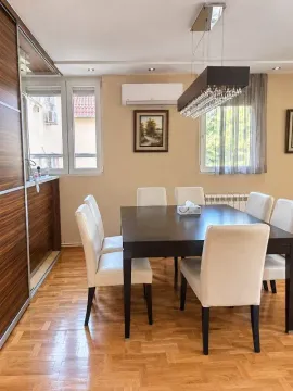 Dining area with a large table and white chairs. - image 4