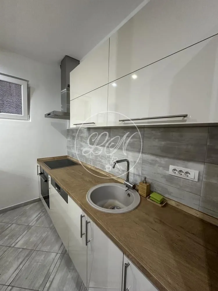 View of a modernly equipped kitchen with white cabinets and a wooden countertop.