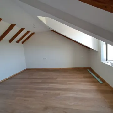 Empty attic room with exposed wooden ceiling beams and laminate flooring. - image 27