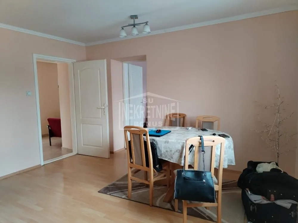 Trpezarija sa stolom i stolicama u okviru dnevnog boravka.