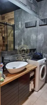 Modern bathroom with a washbasin on a wooden vanity, a mirror, and a washing machine. - image 2