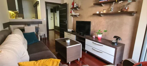 Namještena dnevna soba sa garniturom, TV komodom i policama na zidu. - image 6