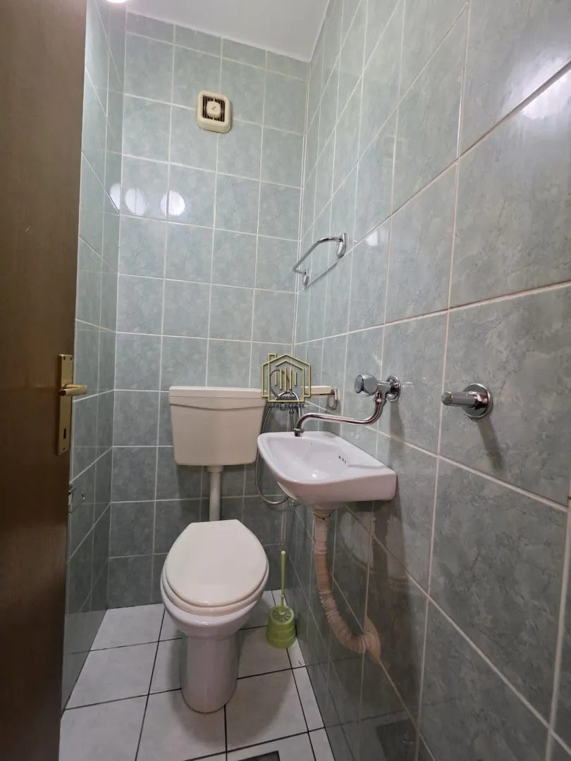 Manje kupatilo obloženo pločicama sa toaletom i umivaonikom.