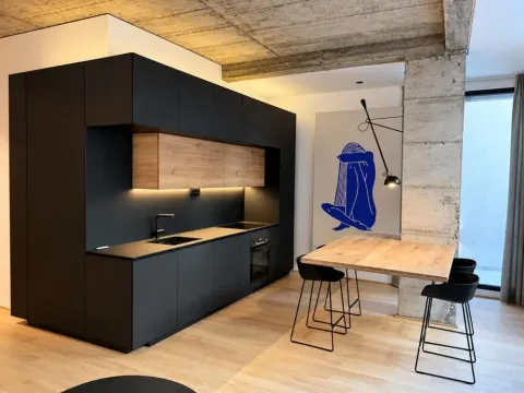Modern black kitchen with wooden accents and a dining table with bar stools. - image 7