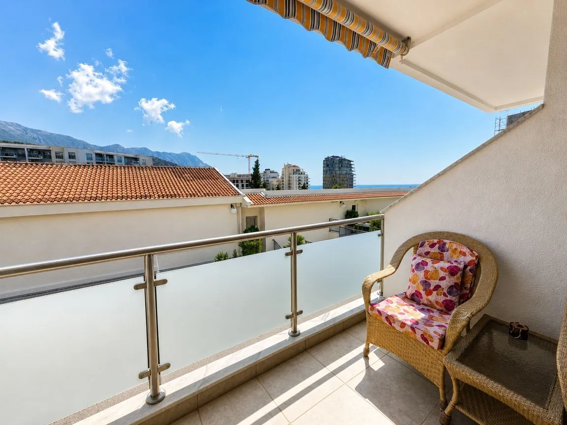 Namješten balkon sa foteljom i pogledom na naselje i more.