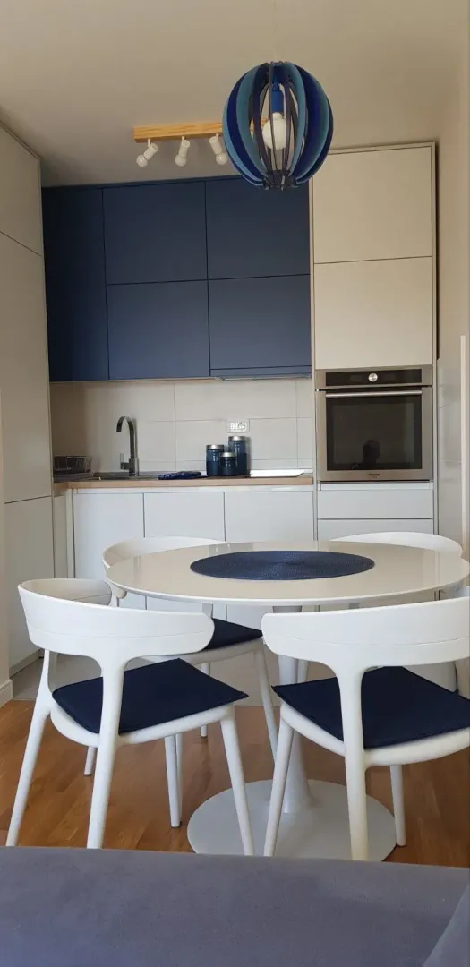 Modern kitchen with a dining table and white chairs.