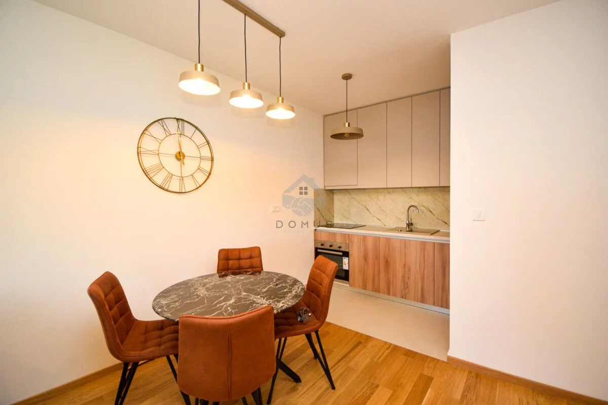 Kuhinja sa trpezarijom opremljena modernim namještajem i rasvjetom.