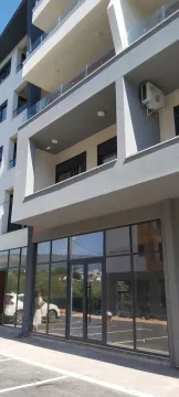Exterior of a modern residential building with a balcony and ground-floor commercial space. - image 10