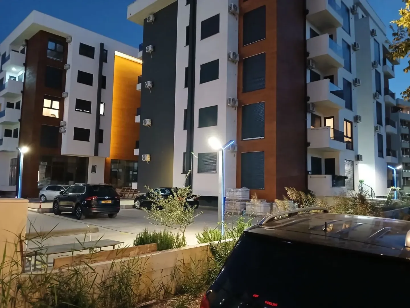 Exterior of the residential building with parking and courtyard in the evening.