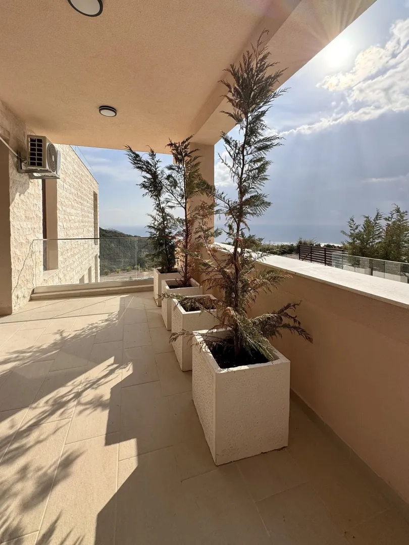 Spacious covered terrace with potted plants and sea view.