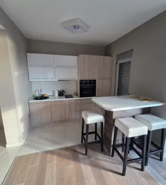 Modern kitchen with built-in cabinetry and a breakfast bar with bar stools. - image 4