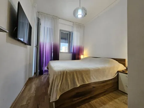 Bedroom with a double bed, TV, and a window with purple curtains. - image 2