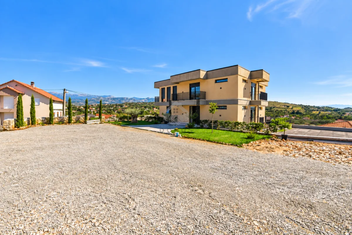 View of the exterior of the house with a courtyard and driveway.