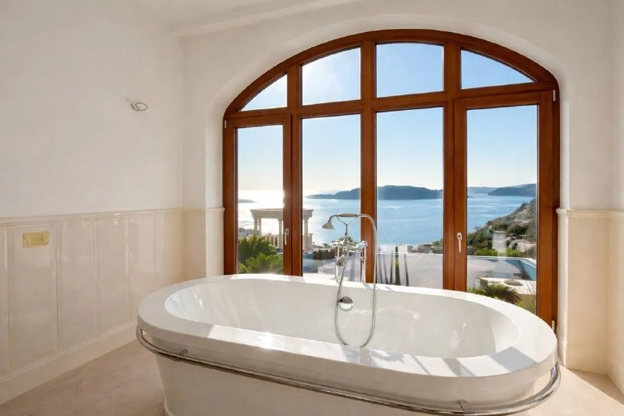 Bathroom with a bathtub and a large window offering sea views.